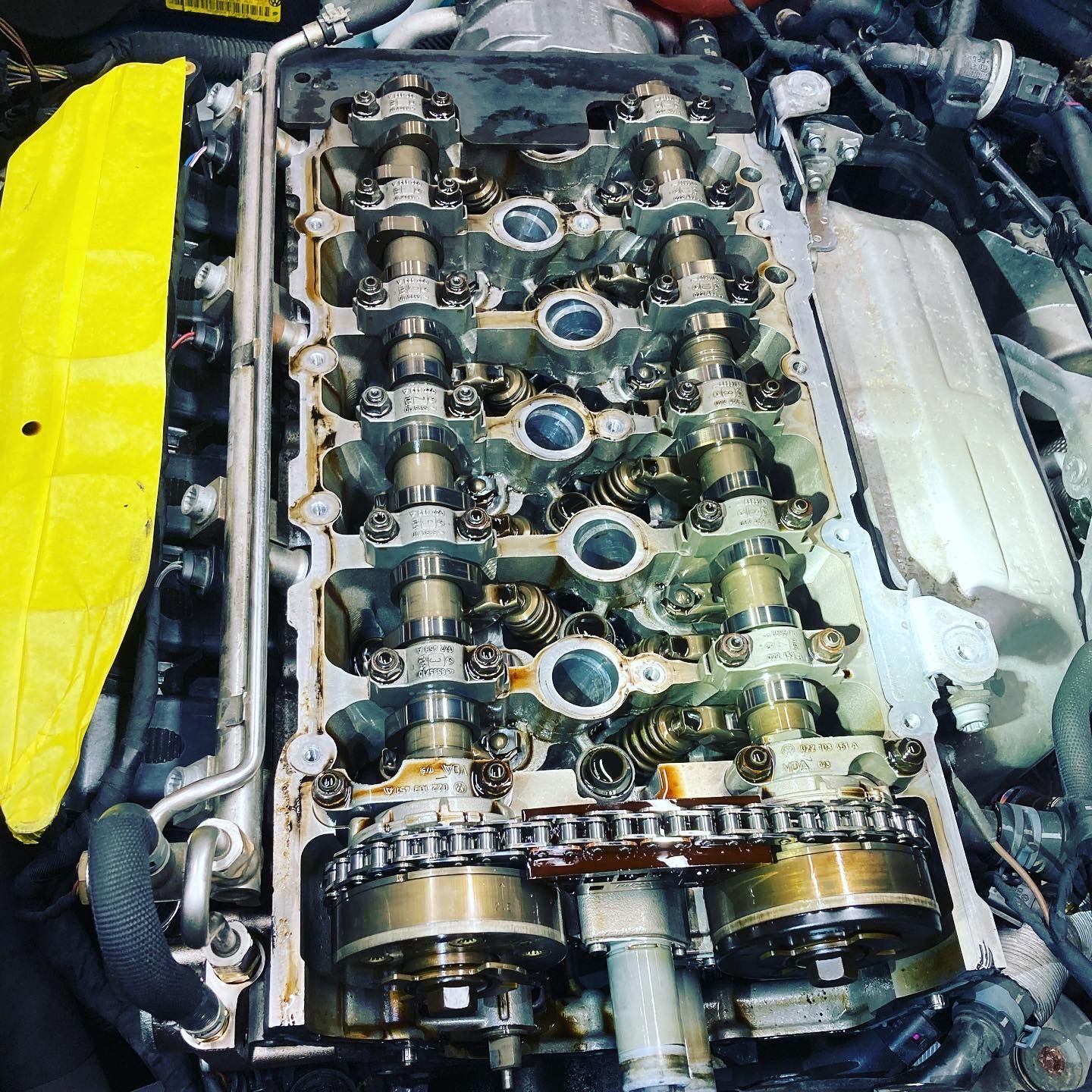 Close-up of an engine cylinder head with camshafts and timing chain exposed during repair