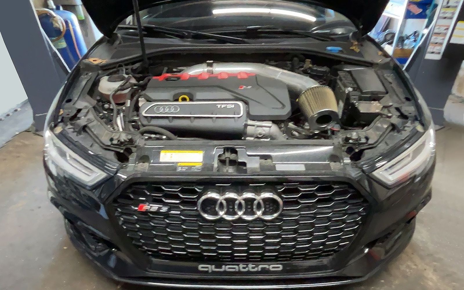 Black Audi SUV with hood open, showing the engine bay in a showroom.