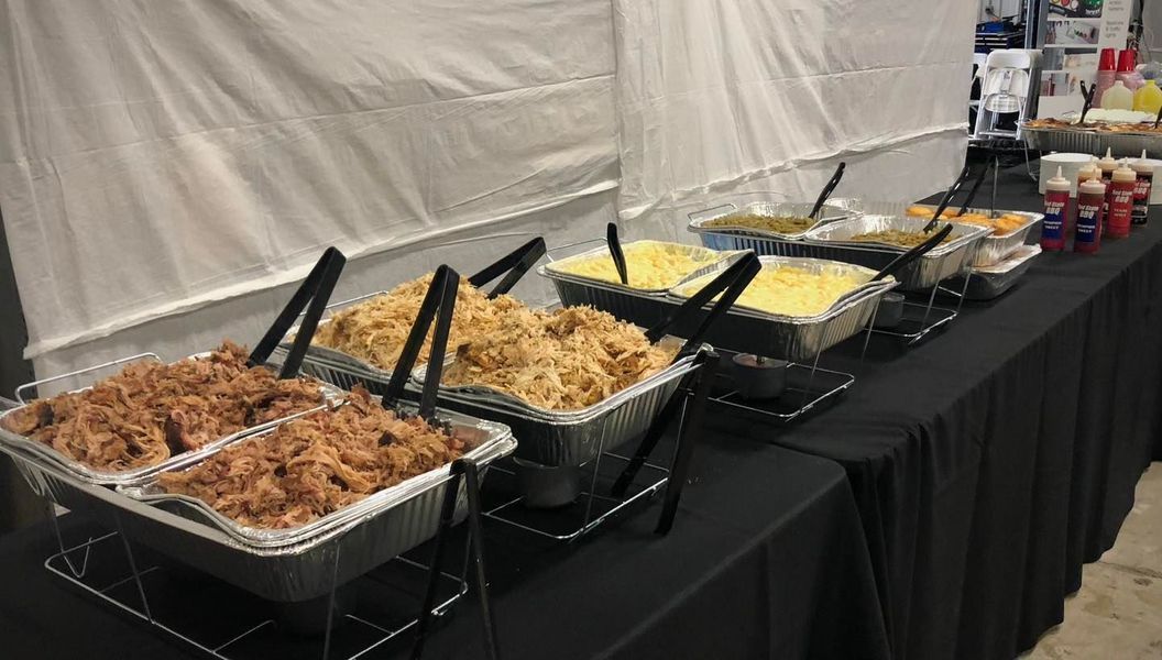 A buffet table featuring rows of aluminum catering trays filled with prepared food and serving tongs.