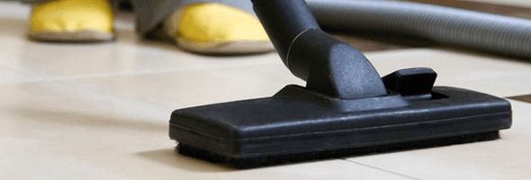 A person is using a vacuum cleaner on a tiled floor