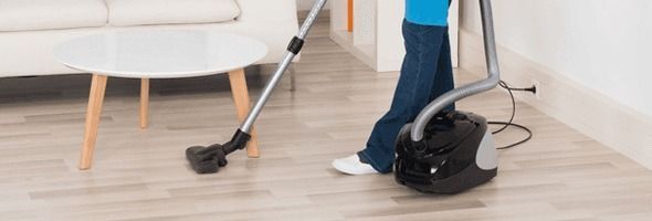 A person is using a vacuum cleaner to clean the floor in a living room