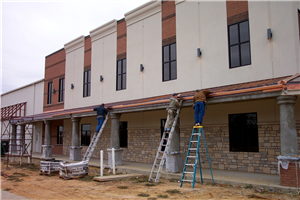 Two men on ladders are working on the side of a building