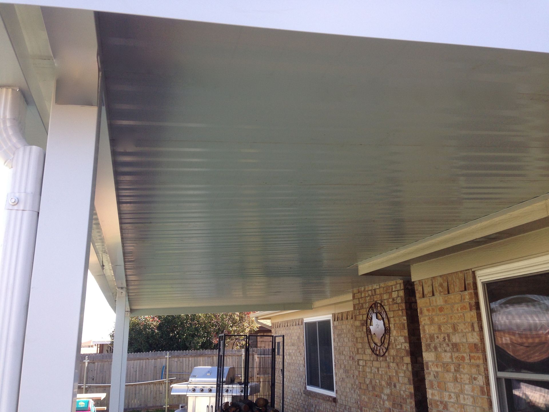 The roof of a house with a covered porch and a grill.