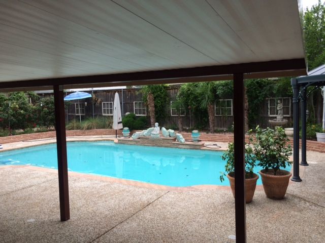 A large swimming pool is under a covered patio.