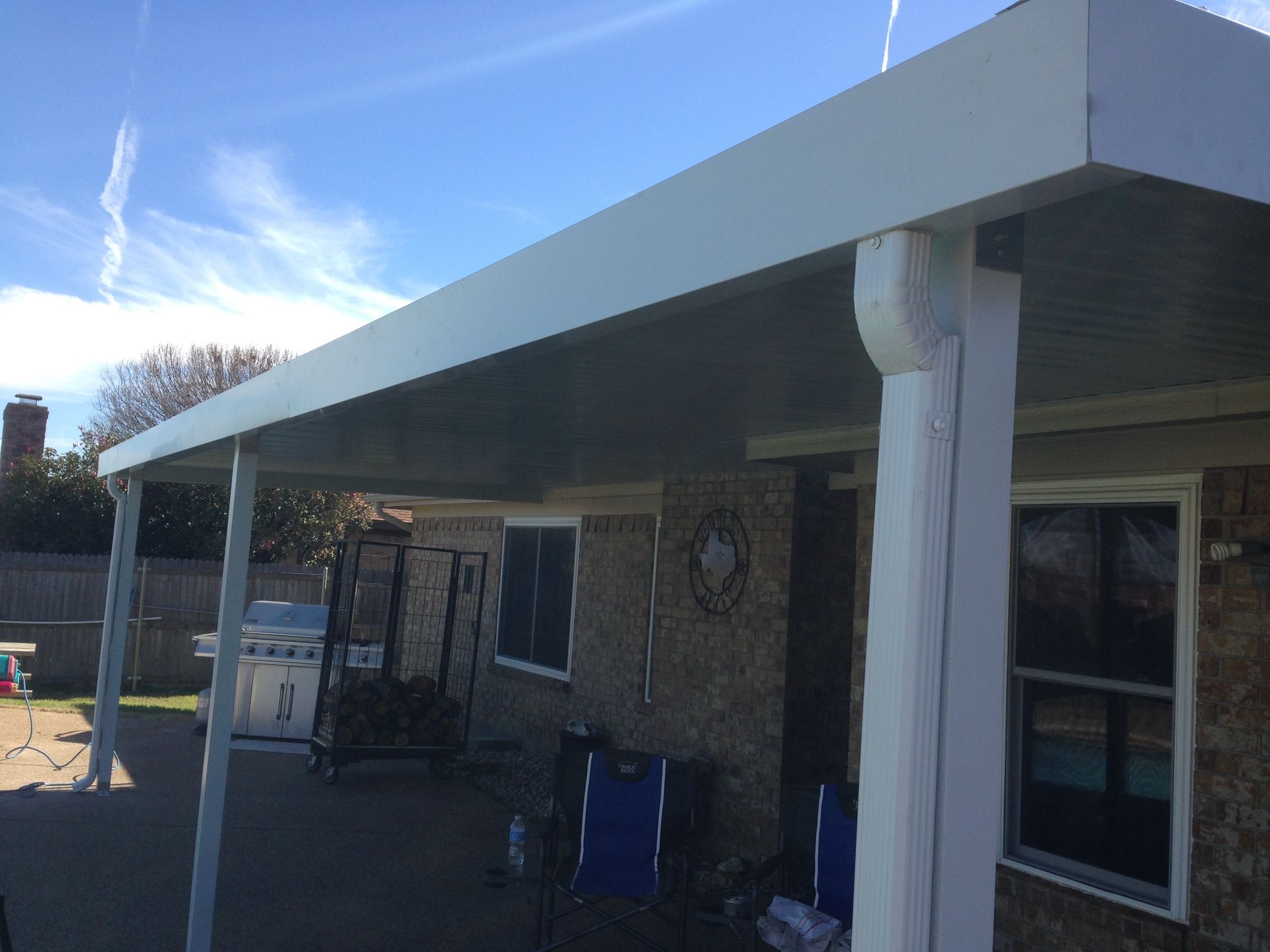 A white patio cover is sitting on top of a brick house.