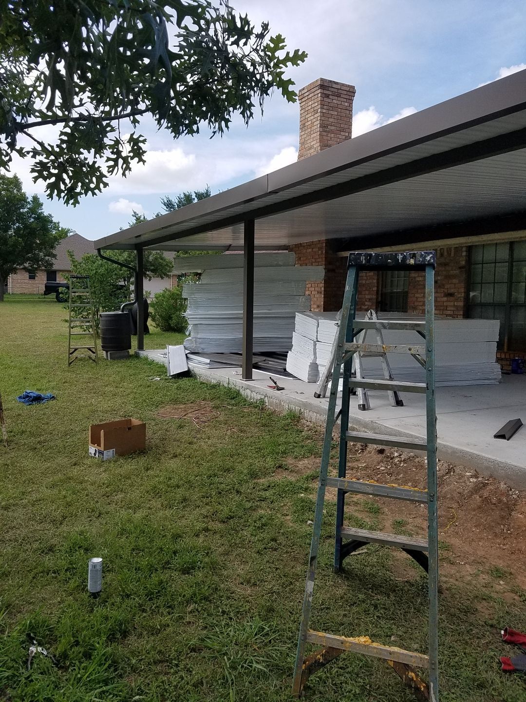 A ladder is sitting in the grass in front of a house.