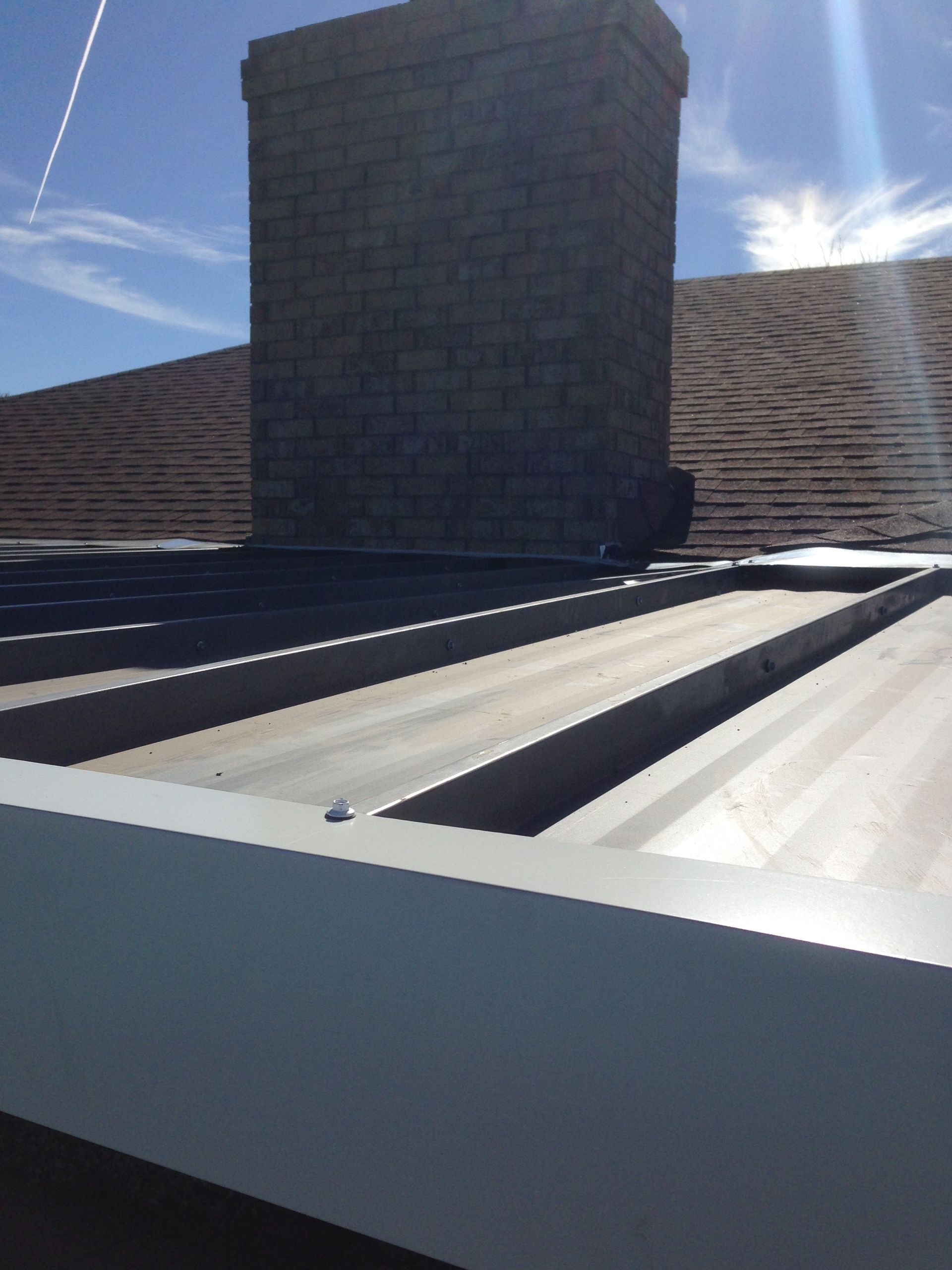 A brick chimney on top of a metal roof