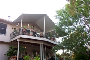A house with a balcony and trees in the background