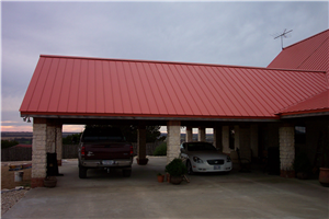 Two cars are parked under a red roof