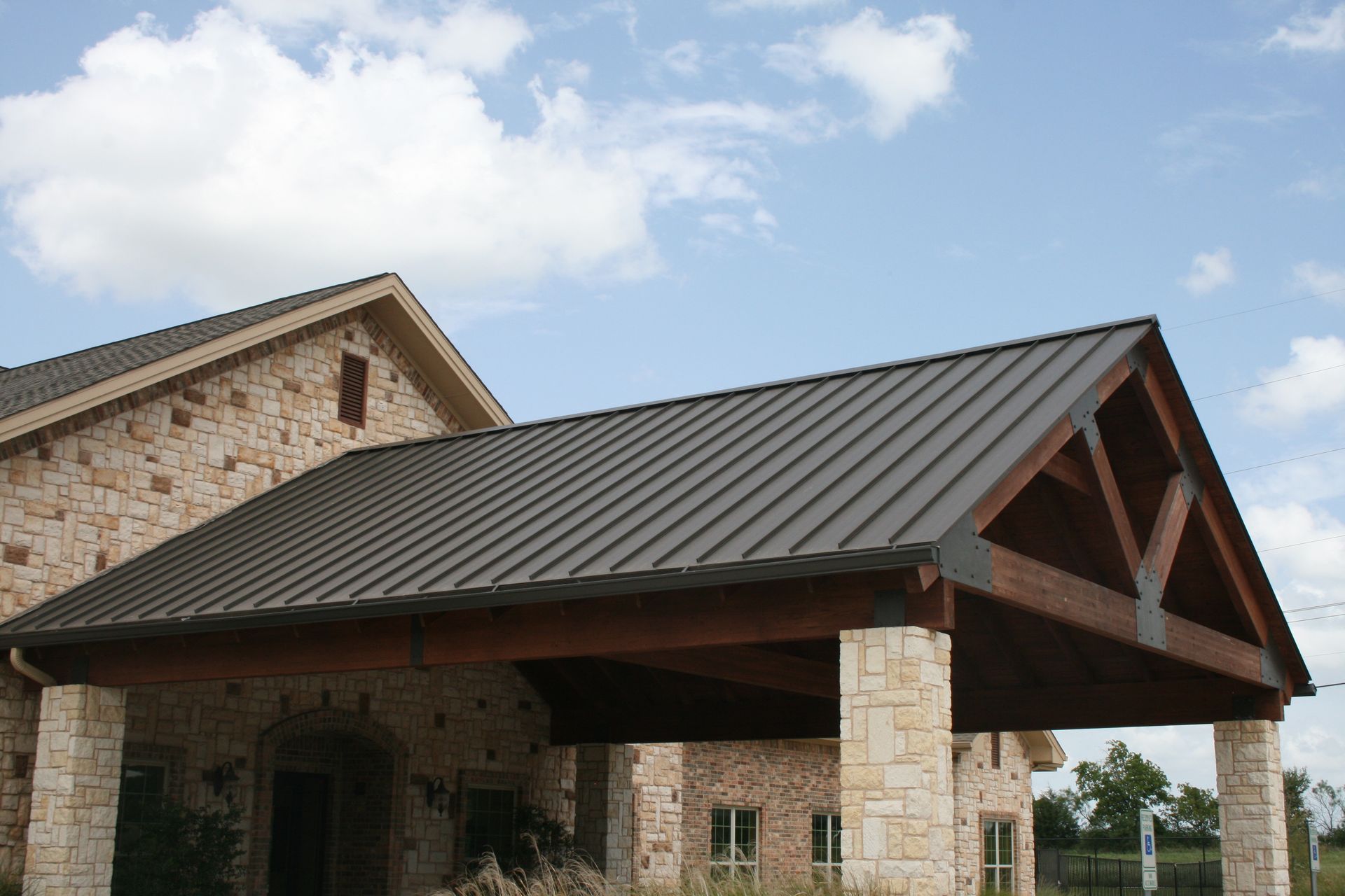 A large stone building with a metal roof and a wooden porch.