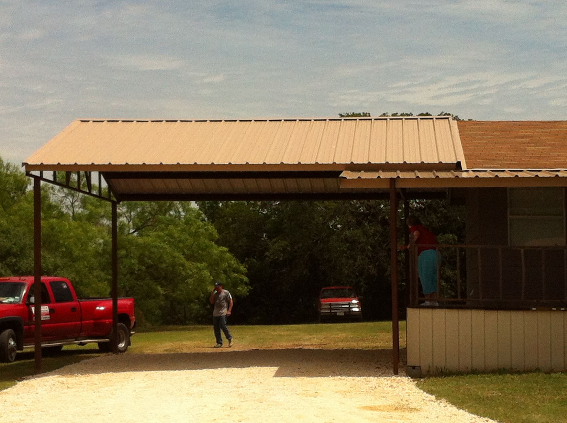 A red truck is parked under a carport