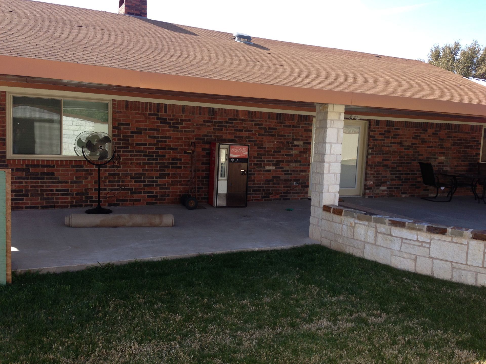A brick house with a patio and a fan in the backyard