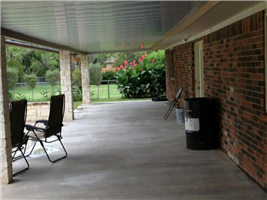 A porch with chairs and a trash can on it