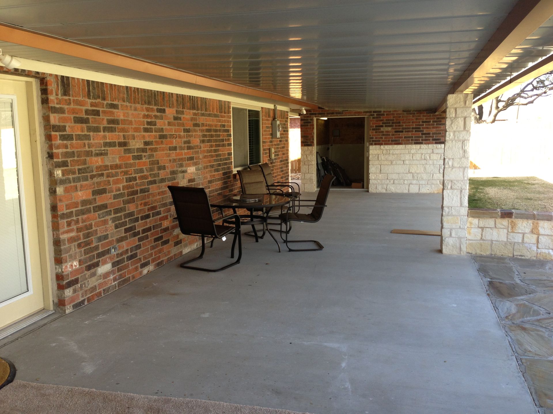 A brick house with a covered porch with chairs and a table