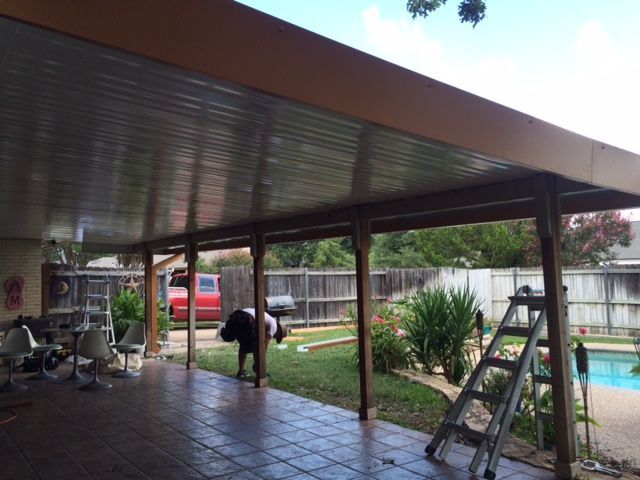 A man is standing under a covered patio next to a pool.