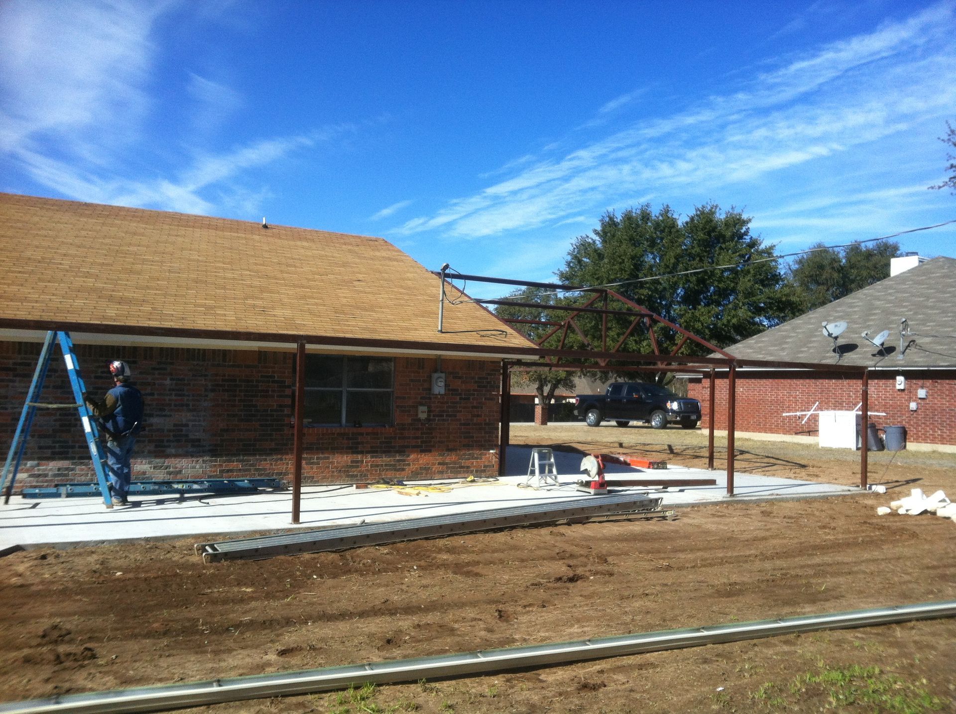 A man is standing on a ladder in front of a house under construction.