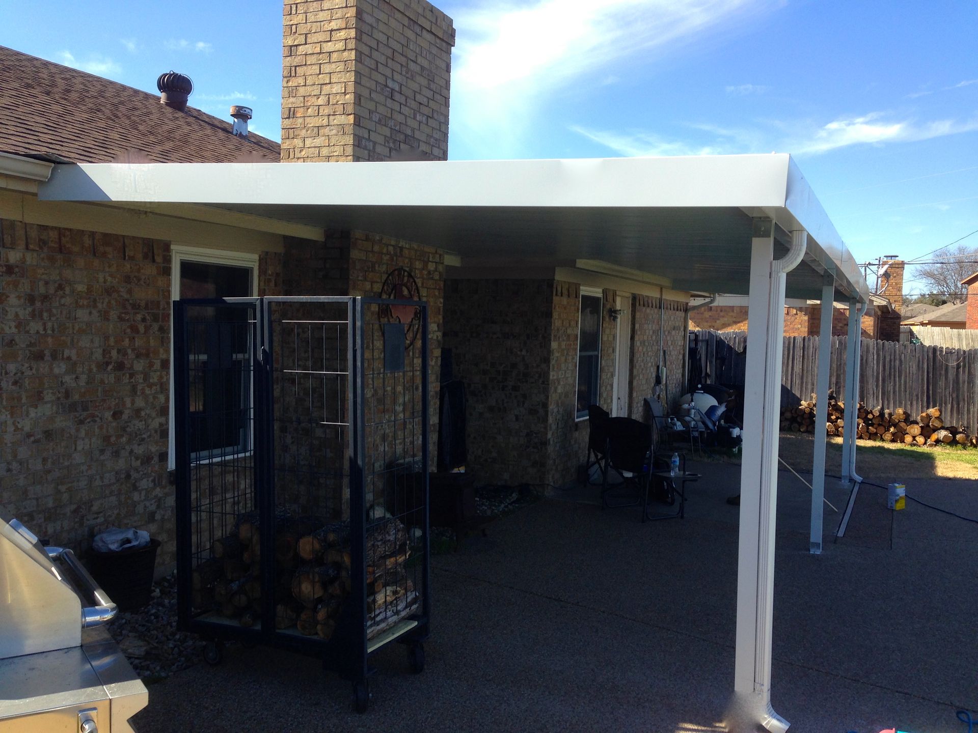 A patio with a white awning over it and a grill.