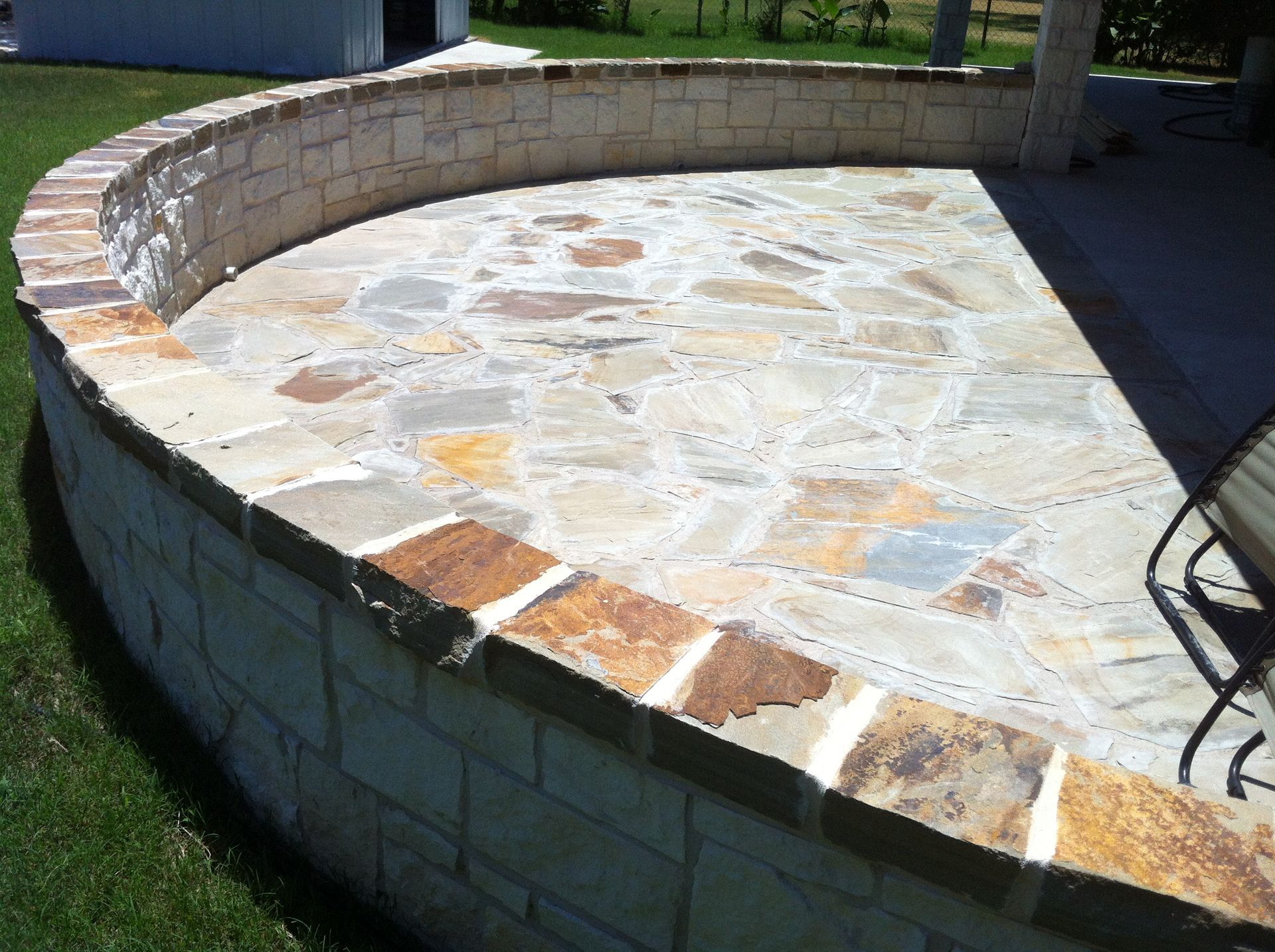 A stone patio with a brick wall surrounding it