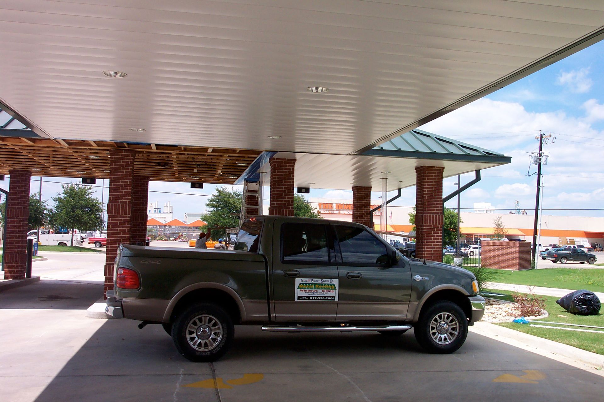A truck is parked under a canopy at a gas station
