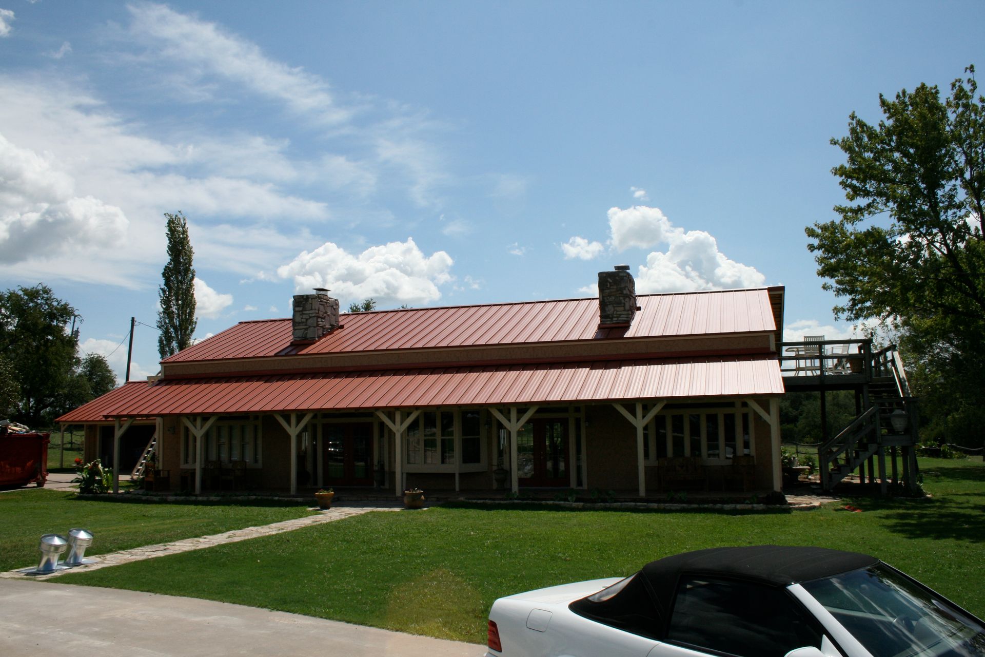 A white car is parked in front of a house with a red roof