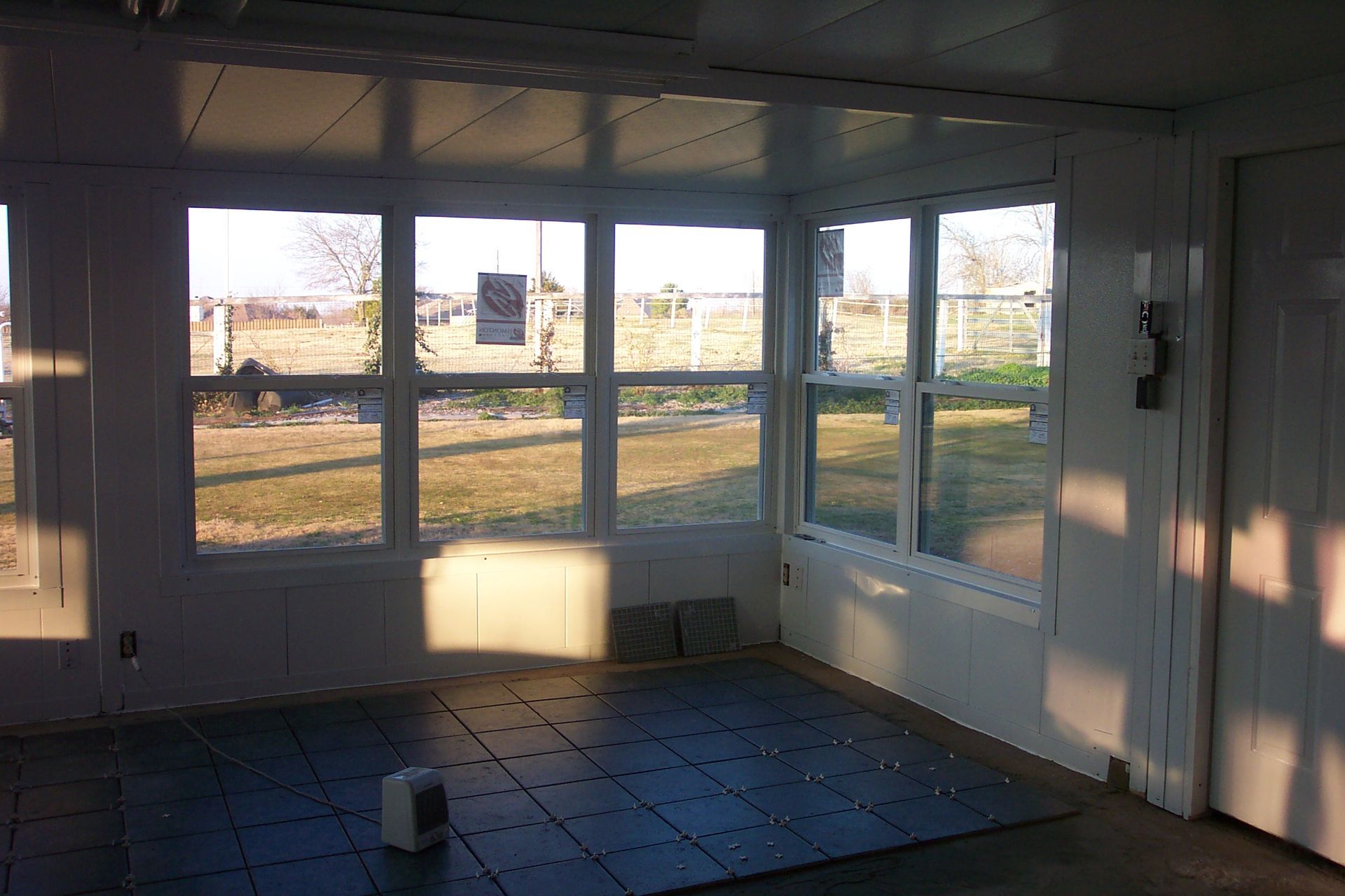 An empty room with a lot of windows and a tiled floor.