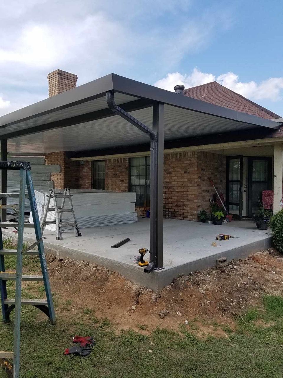 A patio cover is being installed on the side of a house.