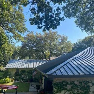 A house with a metal roof and trees in the background