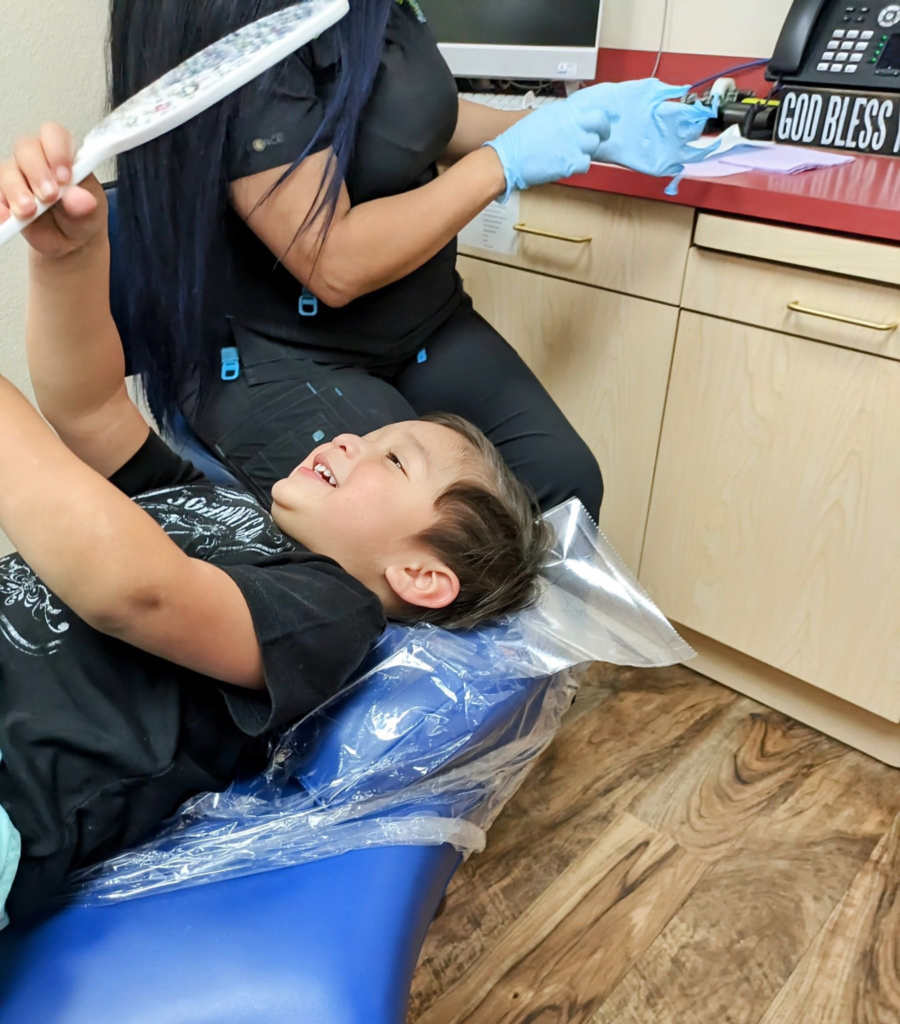 A young boy is sitting in a dental chair smiling at the dentist.