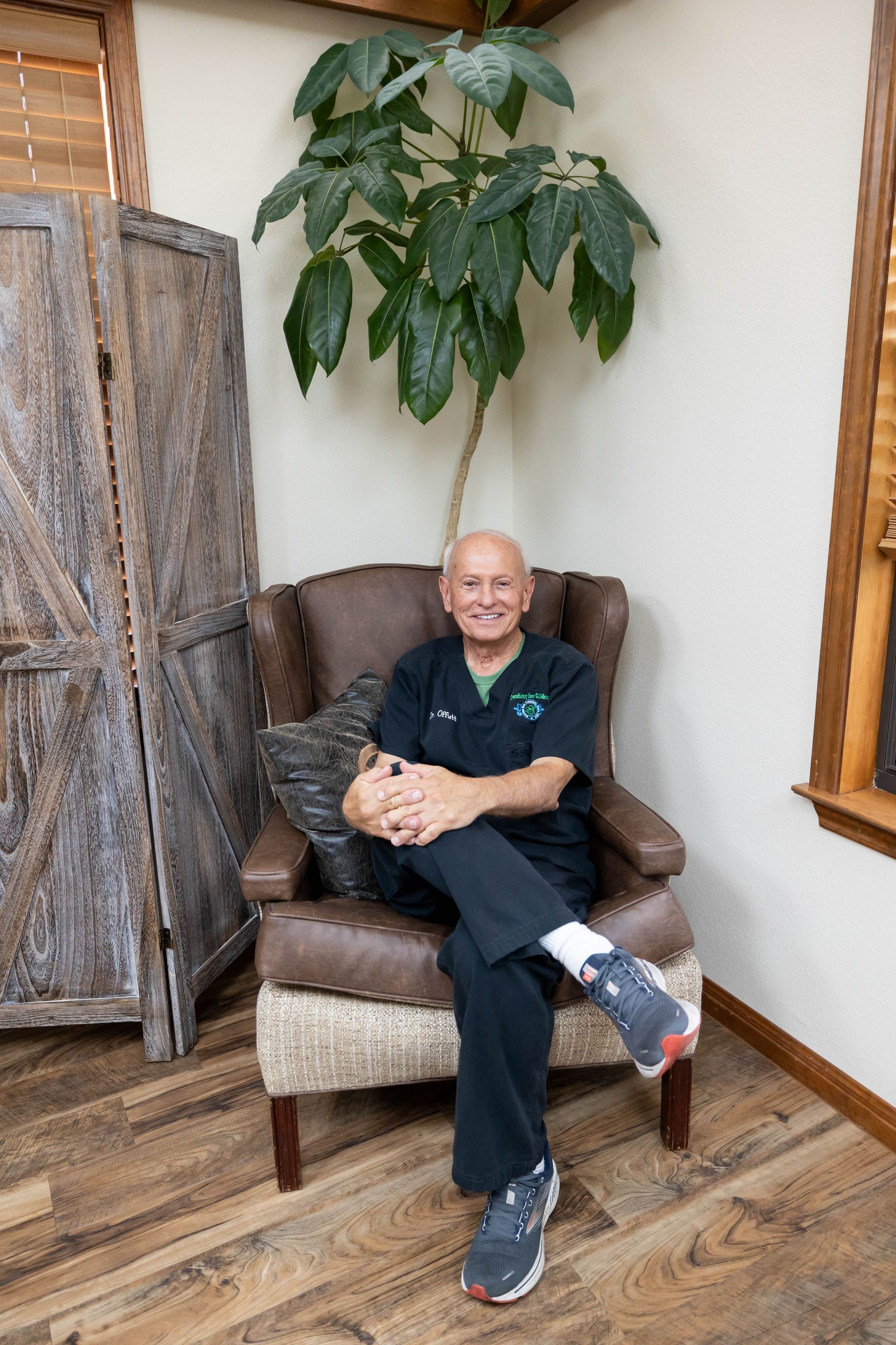 A man is sitting in a chair next to a tree.