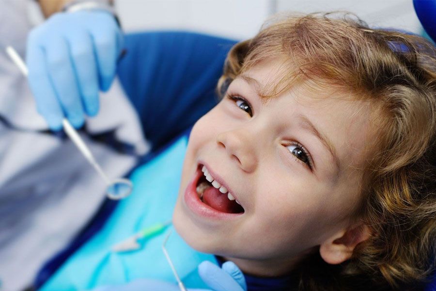 A little boy is getting his teeth examined by a dentist.