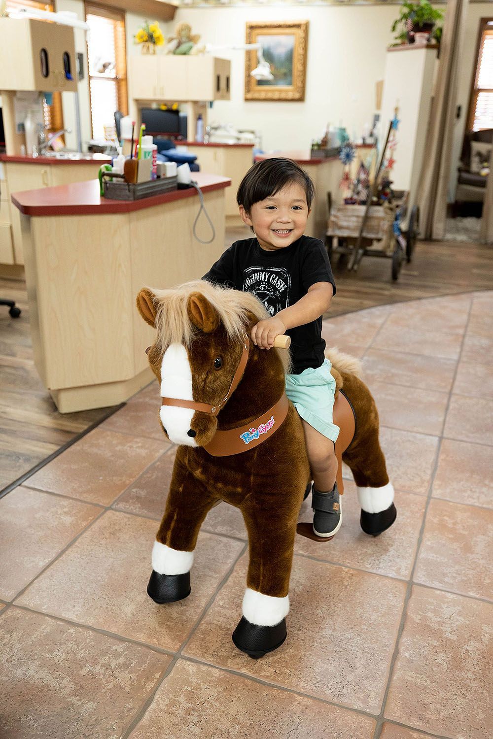 A young boy is riding a stuffed horse in a dental office.