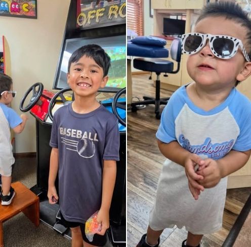 Two children posing indoors, one smiling in a baseball shirt and one in sunglasses and a light blue shirt.