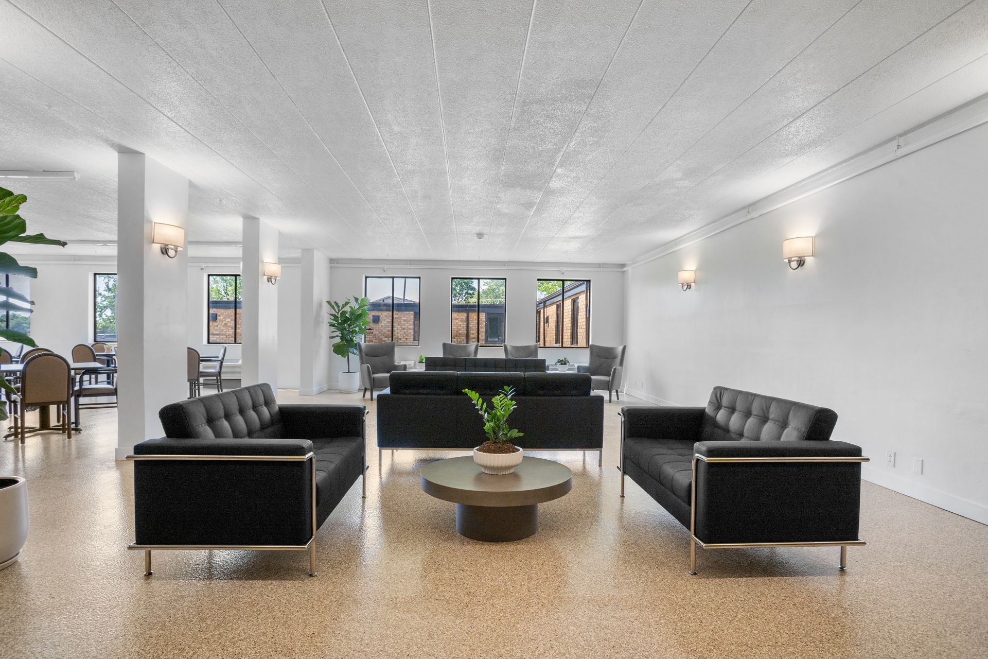Lobby with black leather sofas, round coffee table, and terrazzo flooring. White walls and ceiling.