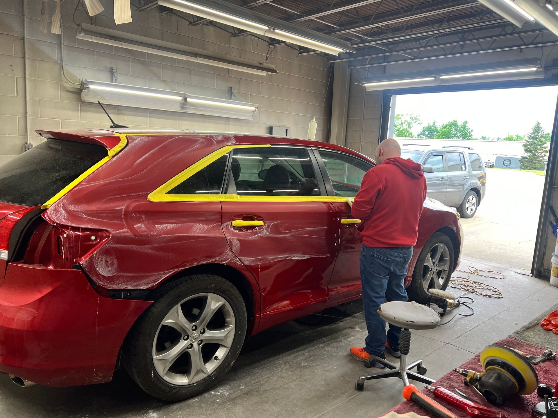 A man is working on a red car in a garage.
