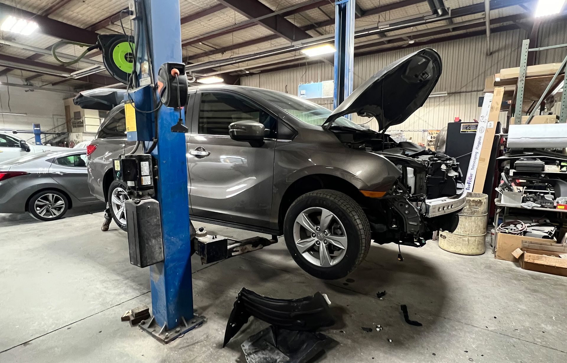 A car is sitting on a lift in a garage with its hood open.
