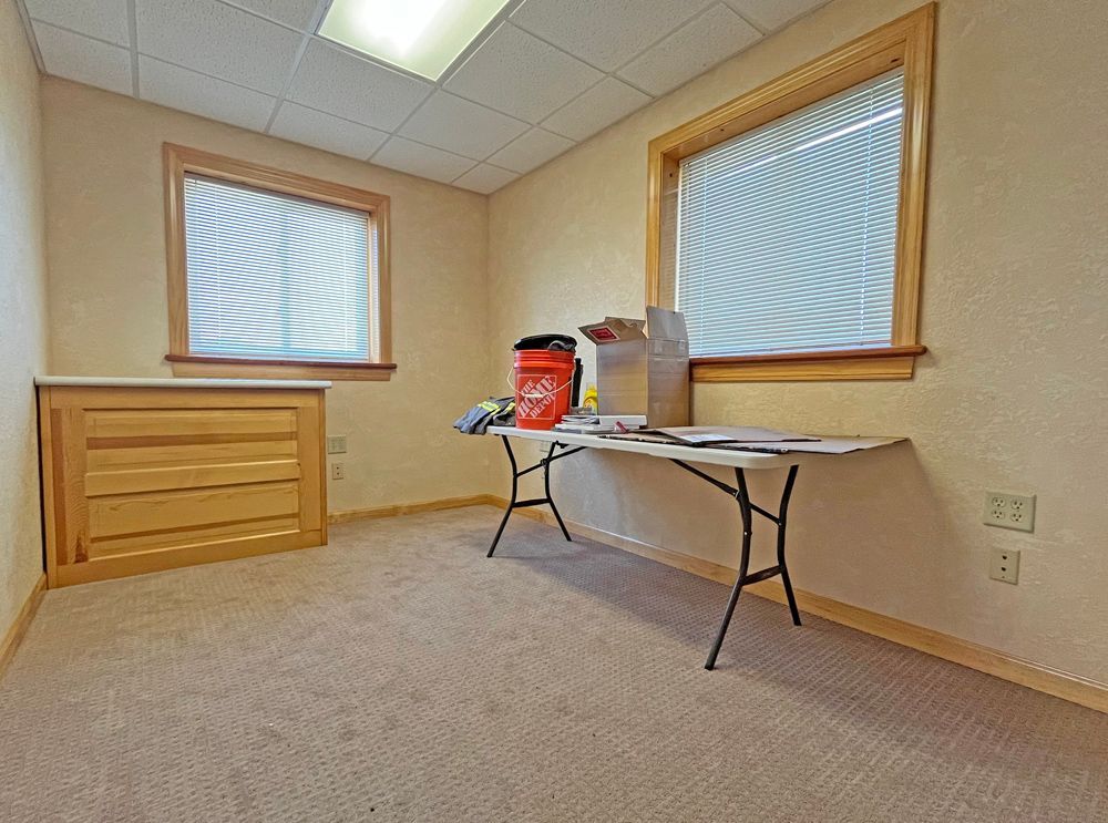 An empty room with a table and two windows.