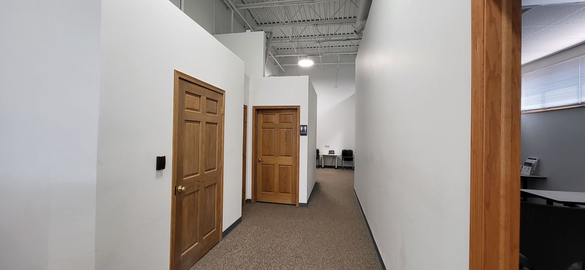 A long hallway with wooden doors and white walls in an office building.