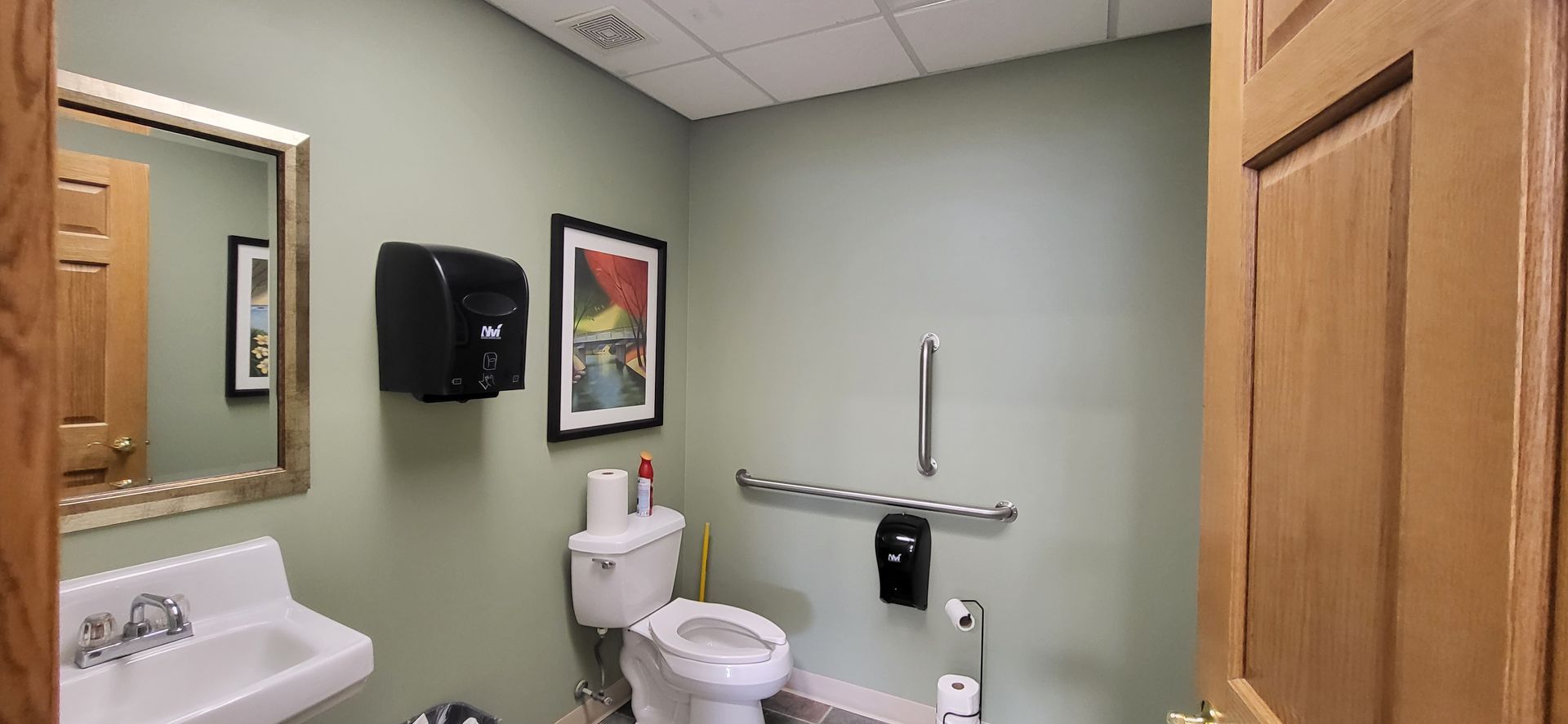 A bathroom with a toilet , sink and mirror.