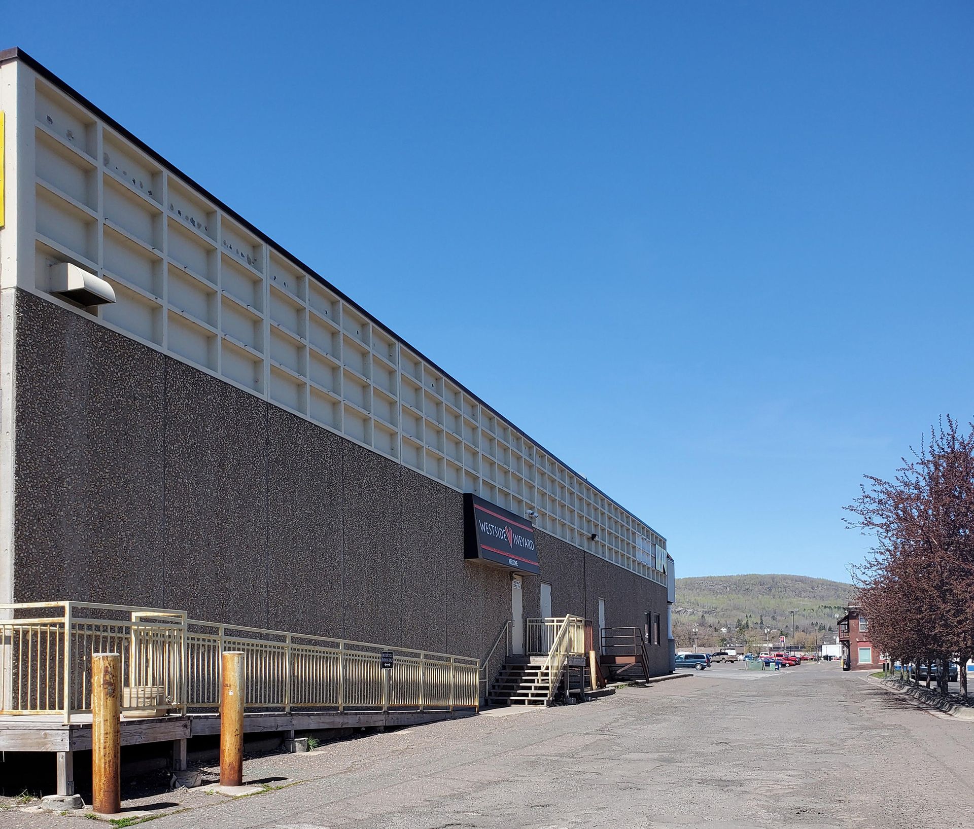 Building with dark stone base and beige upper panels, accessible ramp, gravel lot.