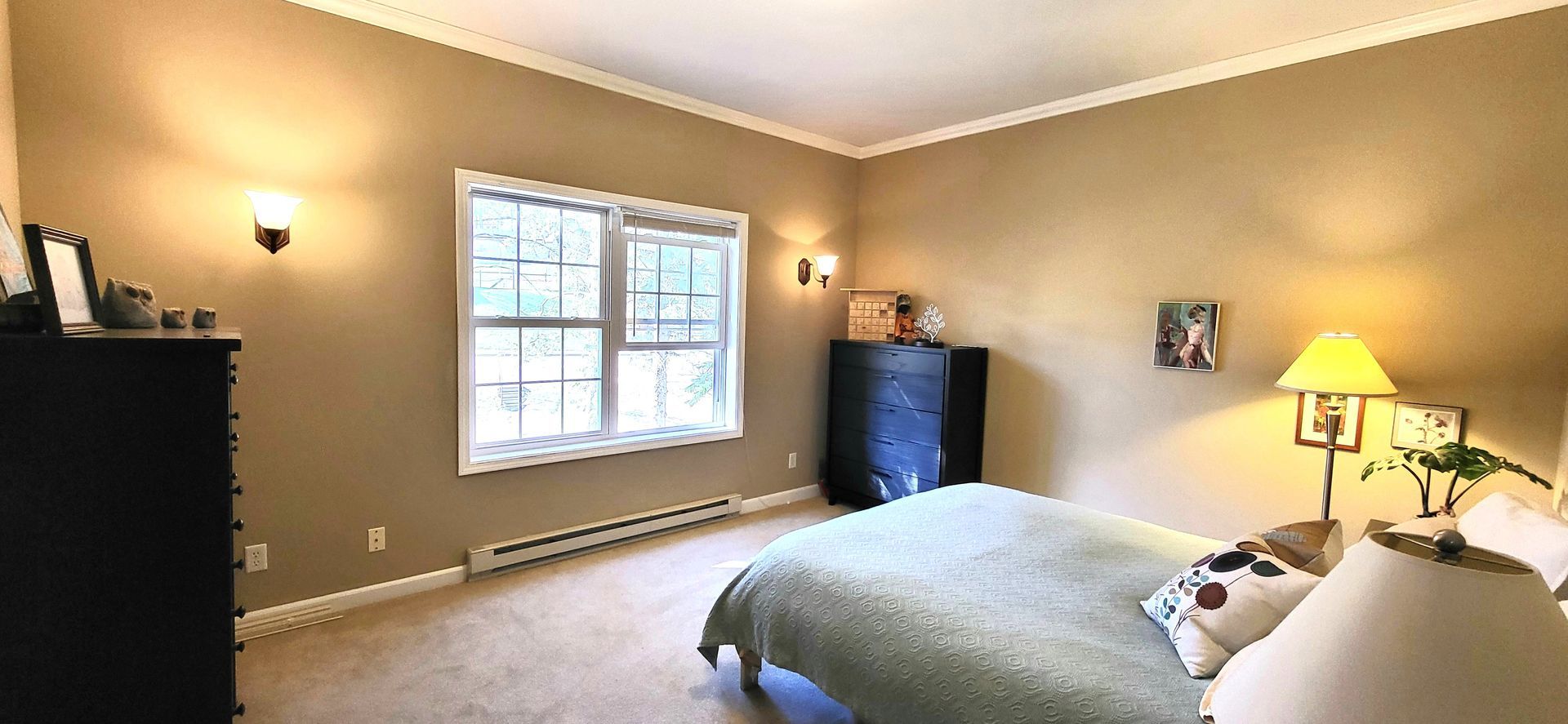 Bedroom with bed, dressers, window, and tan walls.