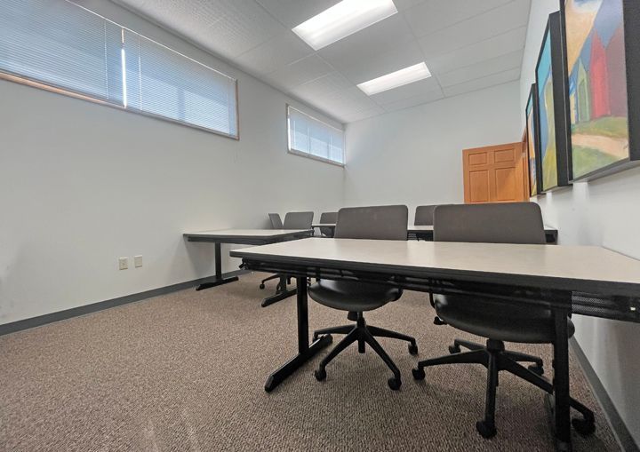 A conference room with tables and chairs and paintings on the wall.