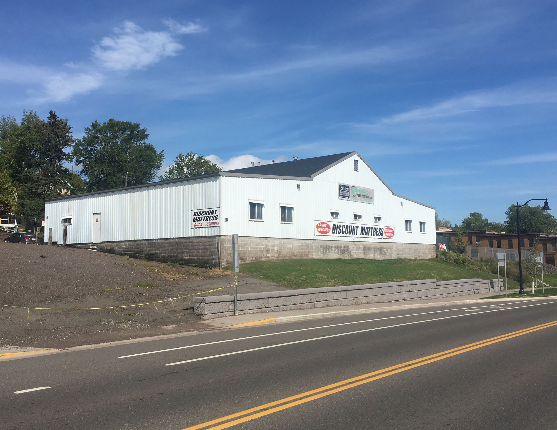 A large white building is sitting on the side of a road.