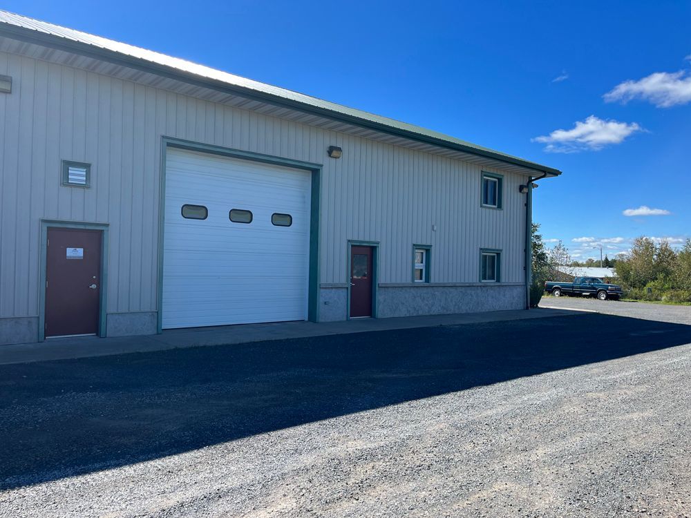 A large building with a white garage door and red doors.
