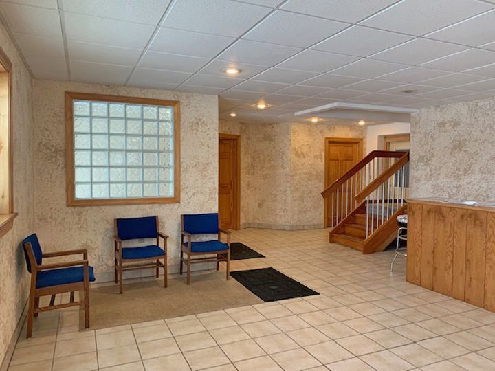 A waiting room with blue chairs and a staircase.