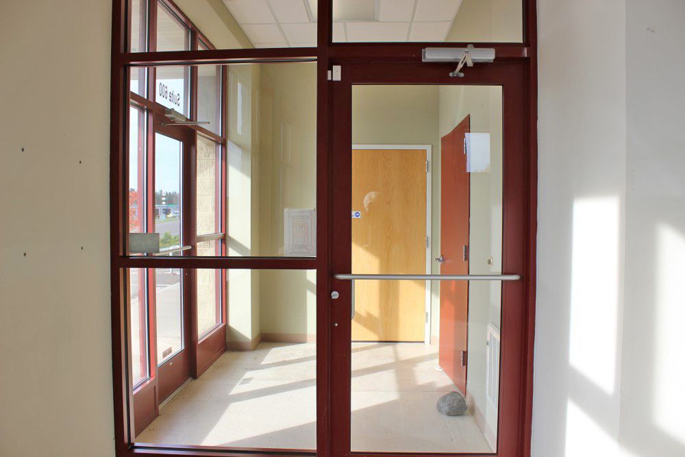 An empty hallway with a glass door and a wooden door