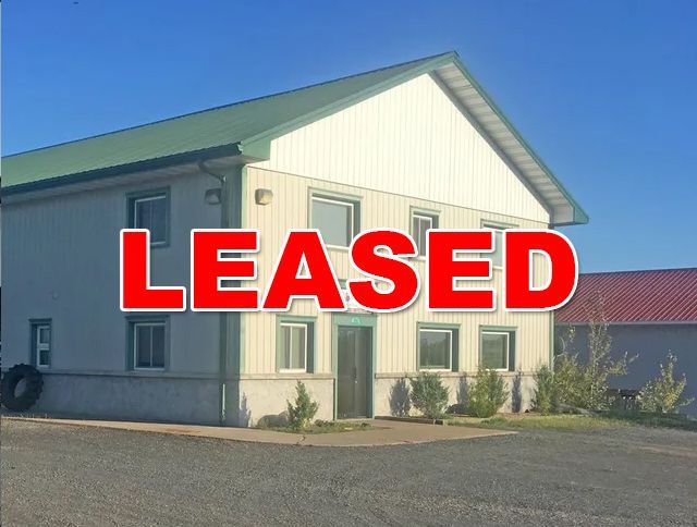 A white building with a green roof has the word leased on it