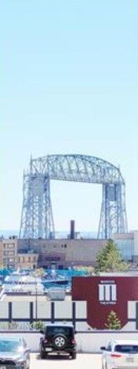 Steel bridge over city rooftops under a pale blue sky