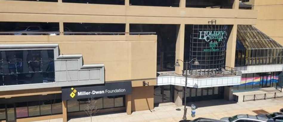 Miller Center entrance and glass facade at an airport terminal, with a few people walking outside.