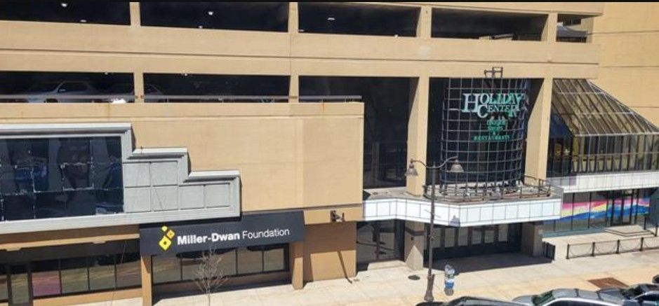 Outside view of a beige building with a black storefront and glass entrance, likely a city business center