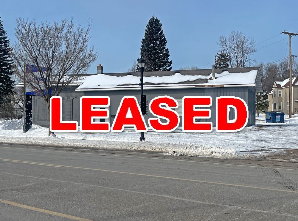 A building with snow on the roof is sitting on the side of the road.